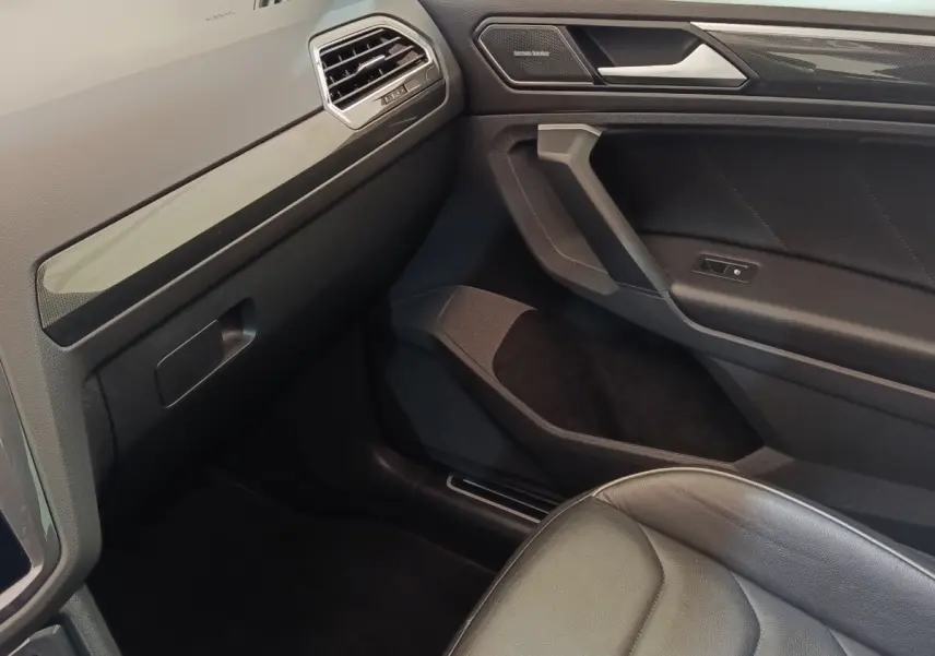 Intérieur côté passager du Volkswagen Tiguan noir 2021, avec siège cuir et garnitures modernes sur la portière.
