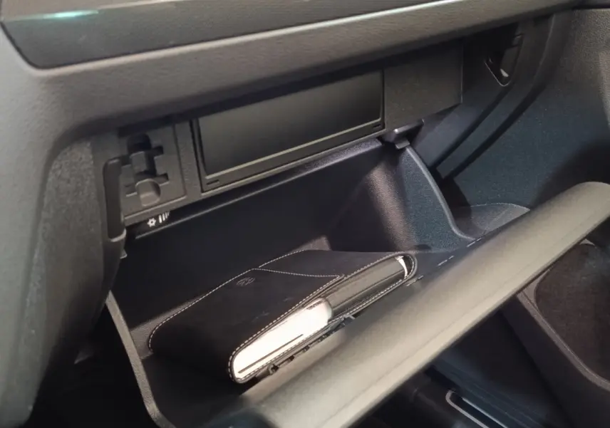 Vue rapprochée de la boîte à gants ouverte du Volkswagen Tiguan 2021, avec un carnet noir à l'intérieur.