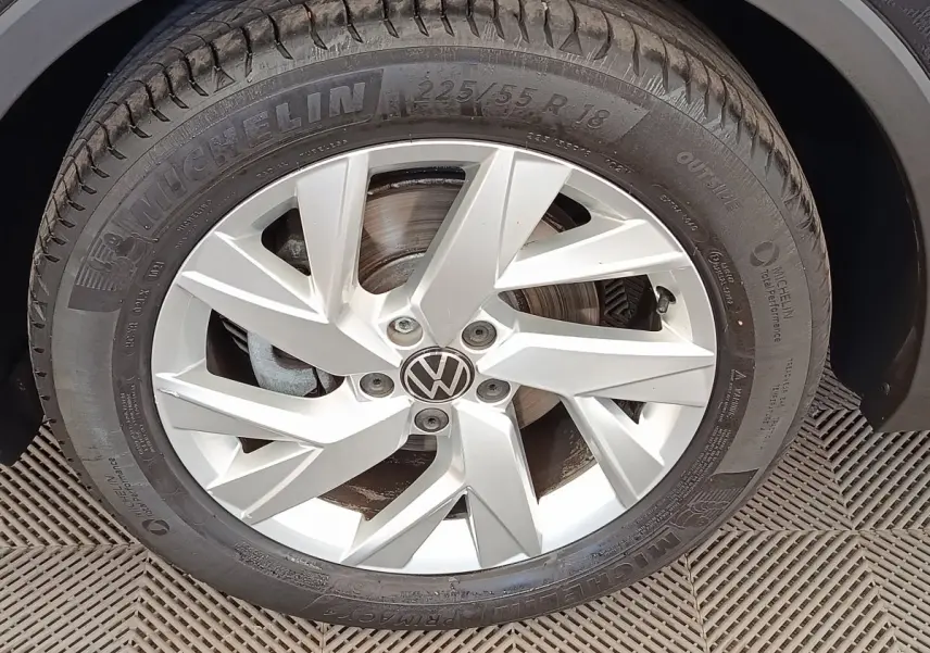 Gros plan sur la roue avant droite du Volkswagen Tiguan noir, jante alliage argentée avec logo VW central.