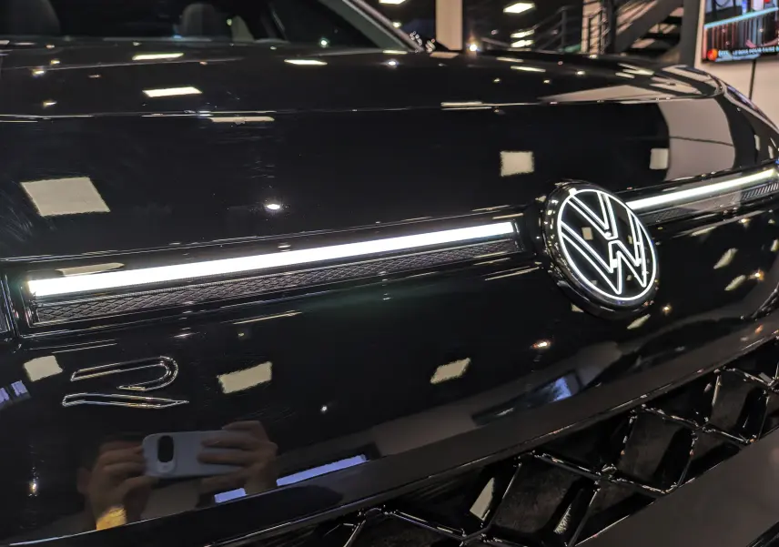 Gros plan sur la calandre noire ébène du Volkswagen T-Roc eTSI 150 R-Line avec logo VW lumineux et bande LED.