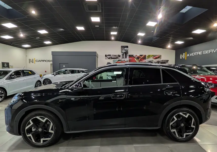Profil côté gauche du Volkswagen T-Roc eTSI 150 CH DSG7 R-Line noir Ébène avec jantes 18 pouces bicolores en showroom.