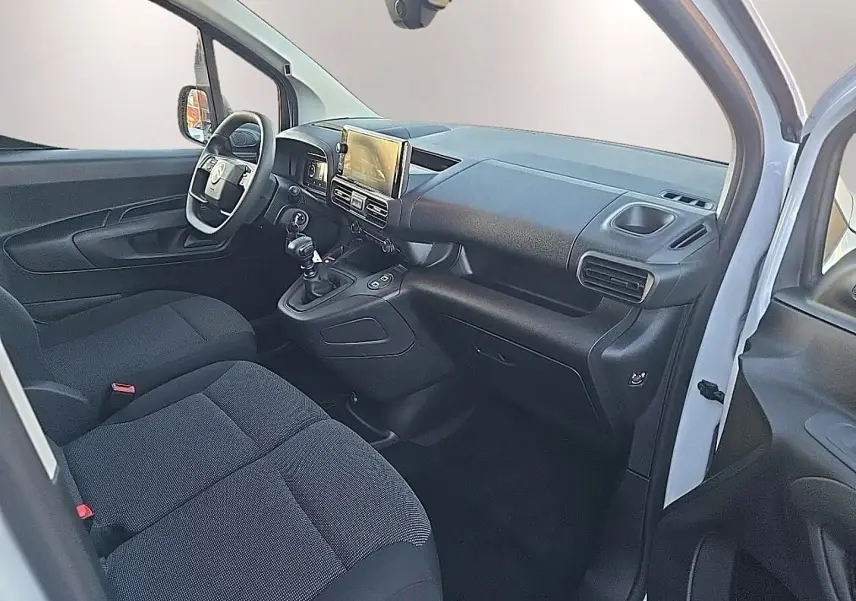 Intérieur avant du Citroën Berlingo Fourgon blanc 2026, vue côté conducteur avec tableau de bord et sièges noirs.