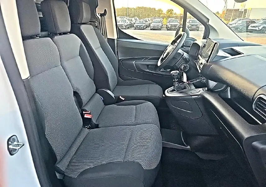 Vue intérieure côté conducteur du Citroën Berlingo Fourgon blanc, montrant les sièges avant et le tableau de bord avec boîte manuelle.