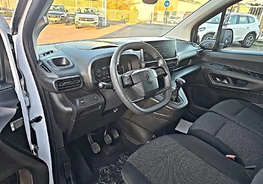 Vue intérieure côté conducteur du Citroën Berlingo Fourgon blanc, volant multifonction et tableau de bord moderne visibles.