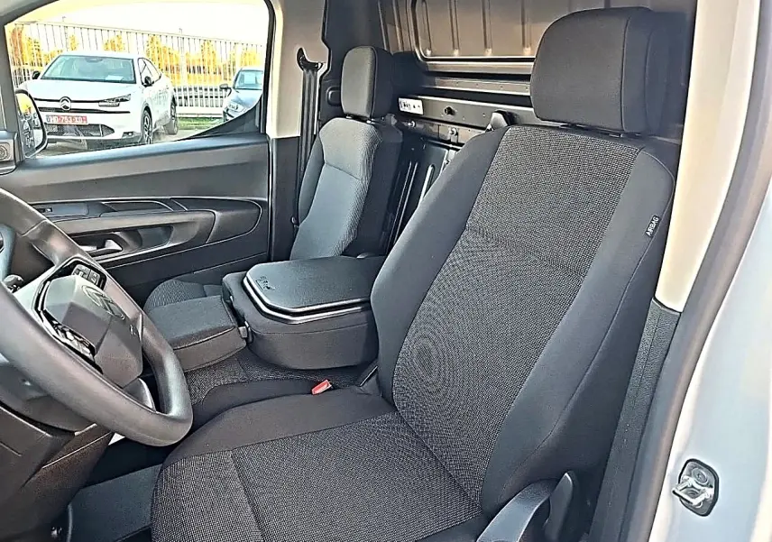 Vue intérieure côté conducteur du Citroën Berlingo Fourgon blanc, montrant les sièges et le volant multifonction.