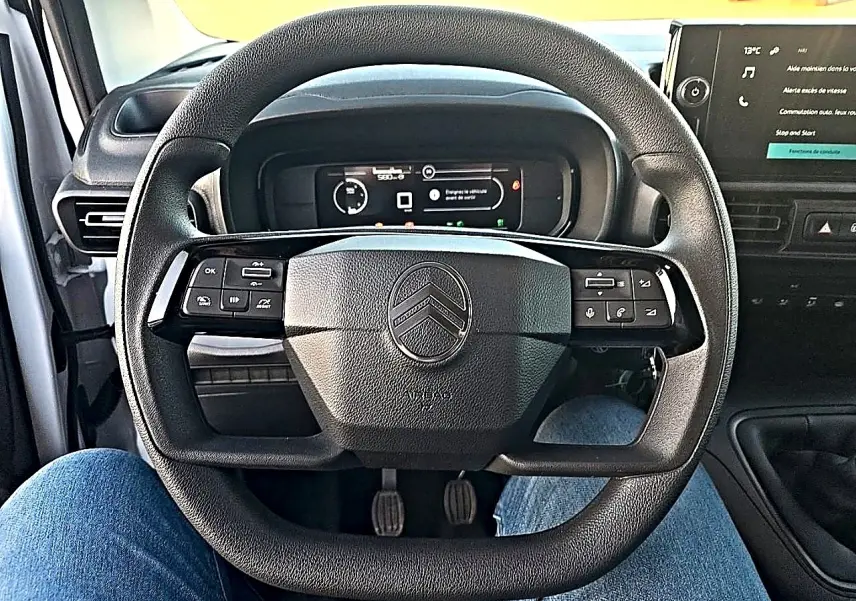 Vue intérieure centrée sur le volant multifonction noir du Citroën Berlingo Fourgon 2026 avec tableau de bord numérique.