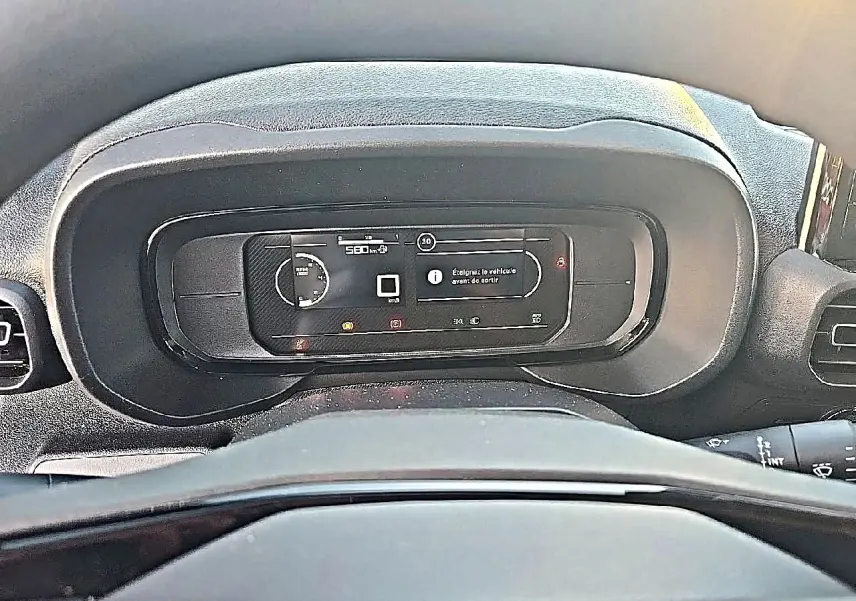 Vue rapprochée du tableau de bord numérique du Citroën Berlingo Fourgon blanc, affichant les informations de conduite.