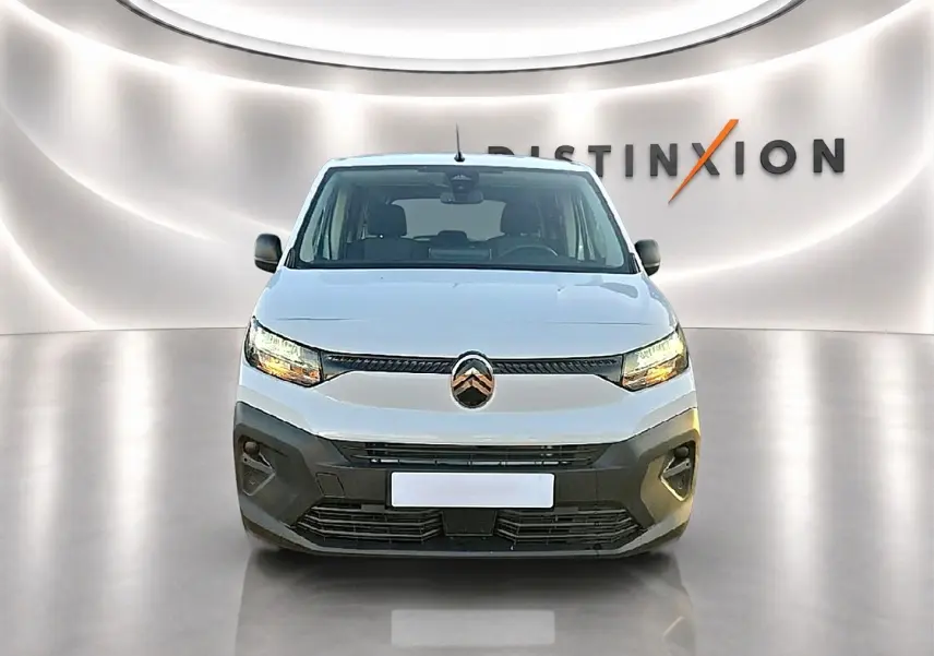 Vue de face d'un Citroën Berlingo Fourgon XL blanc avec phares allumés dans un showroom lumineux.