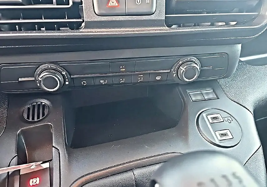 Vue rapprochée de la console centrale noire du Citroën Berlingo Fourgon avec commandes clim et prises USB visibles.