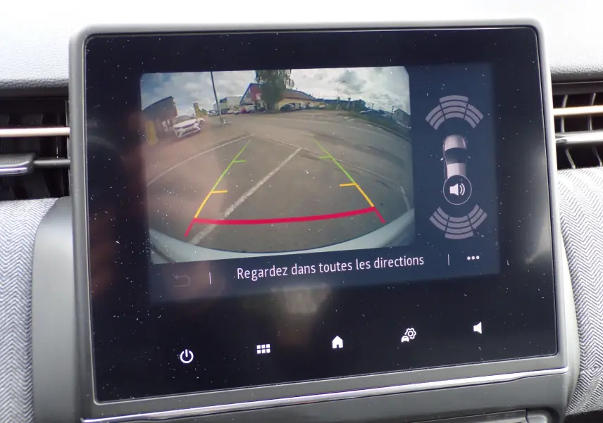 Écran central montrant la caméra de recul avec lignes de guidage et alertes de proximité sur Renault Clio V blanche.