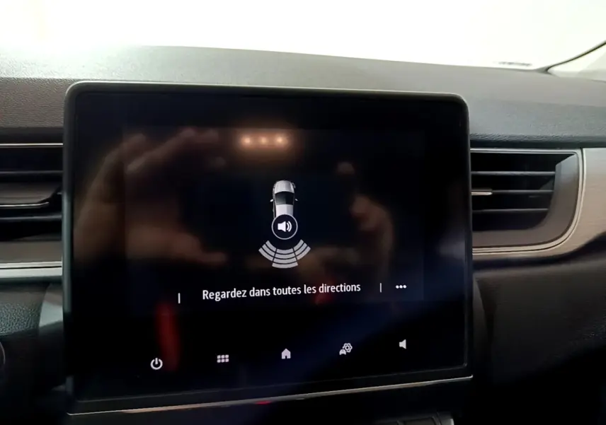 Écran tactile central du tableau de bord du Renault Captur gris clair, affichant une alerte de détection d'obstacles.