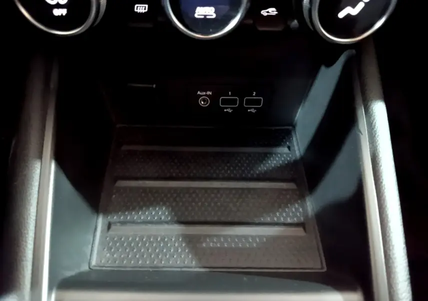 Gros plan sur la console centrale noire du Renault Captur Intens E-Tech 2021, montrant ports USB et bouton de climatisation.