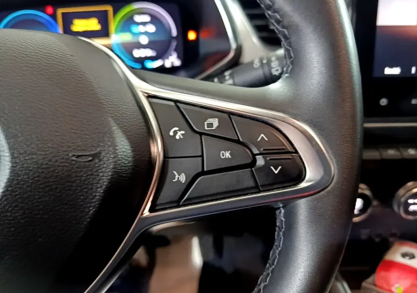 Gros plan sur le volant cuir noir du Renault Captur Intens E-Tech 2021, avec commandes multifonctions et tableau de bord numérique flou.