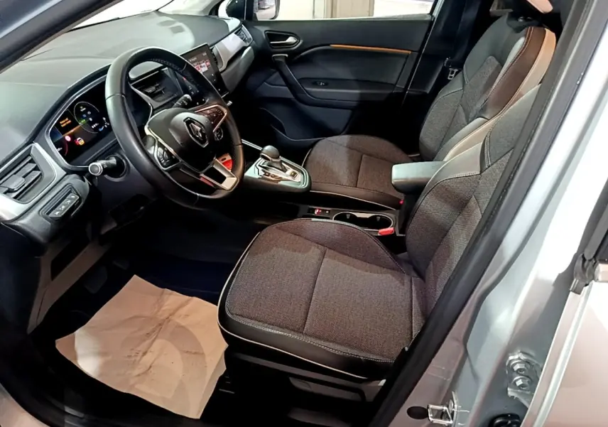 Intérieur côté conducteur du Renault Captur gris clair 2021, montrant sièges tissu et tableau de bord avec écran tactile.