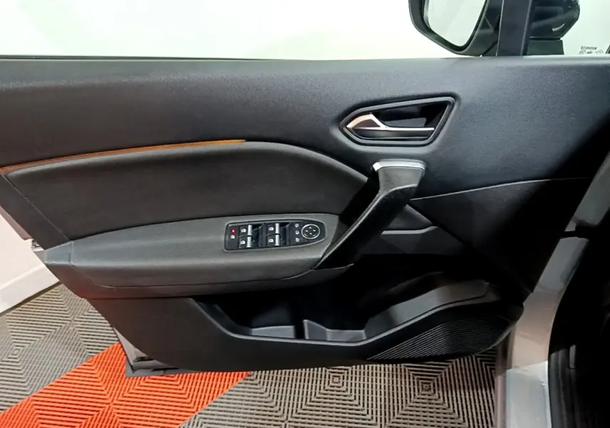 Vue intérieure côté gauche de la porte avant grise du Renault Captur Intens E-Tech avec commandes de vitres et rétroviseur.