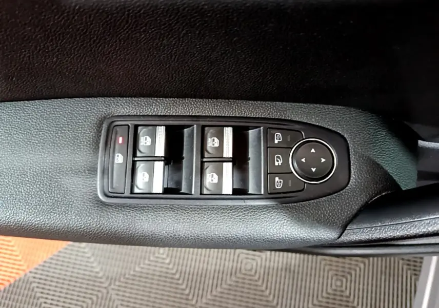 Vue rapprochée des commandes de lève-vitres et rétroviseurs sur la porte côté gauche d’un Renault Captur gris clair.