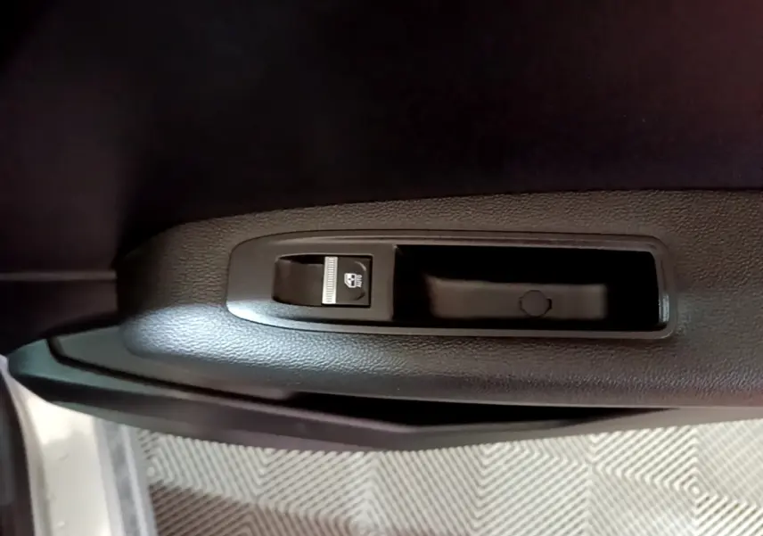 Détail du bouton de verrouillage des vitres sur la porte intérieure côté gauche d’un Renault Captur gris clair.
