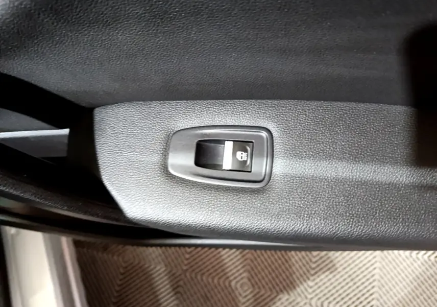 Gros plan sur le bouton de verrouillage des portes noir intégré à la garniture intérieure d'une Renault Captur gris clair.