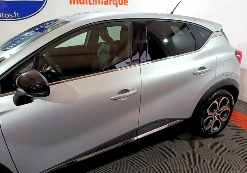 Profil droit du Renault Captur Intens E-Tech hybride rechargeable gris clair, avec rétroviseur noir et jantes distinctives.