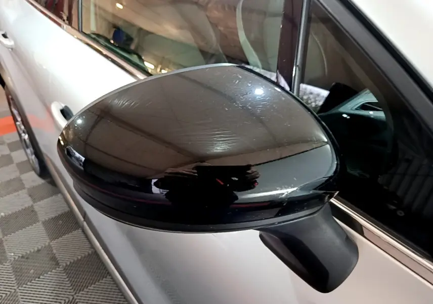 Rétroviseur noir en gros plan côté gauche d’un Renault Captur gris clair hybride rechargeable vu de profil.