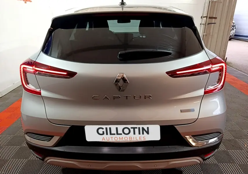 Vue arrière d’un Renault Captur gris clair avec feux LED allumés dans un garage.