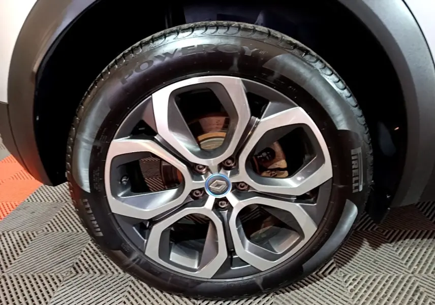 Gros plan sur la roue avant droite du Renault Captur gris clair, avec jante alliage au design moderne et logo Renault central.