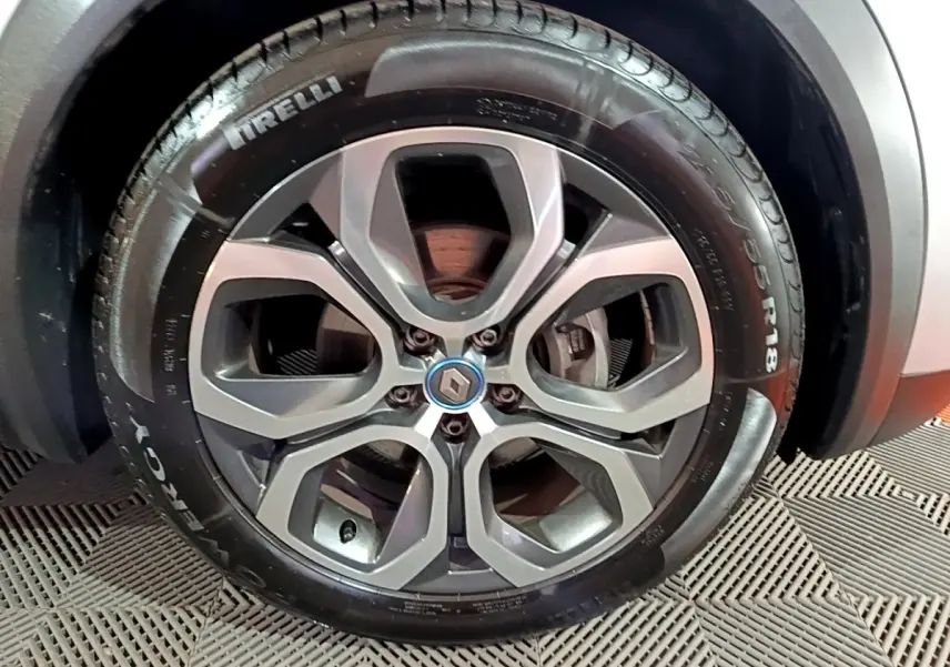 Gros plan sur la roue avant droite du Renault Captur gris clair, avec jante alliage et logo Renault central.