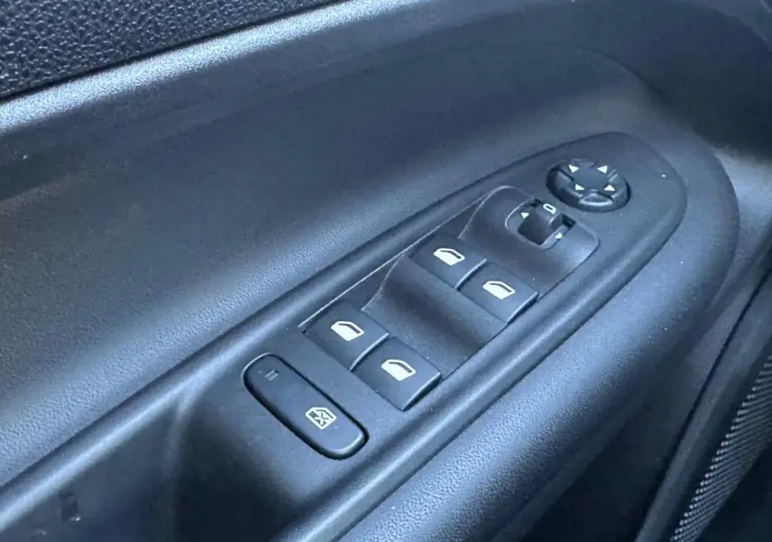 Gros plan sur les commandes électriques des vitres et rétroviseurs côté conducteur du Jeep Avenger gris 2025.