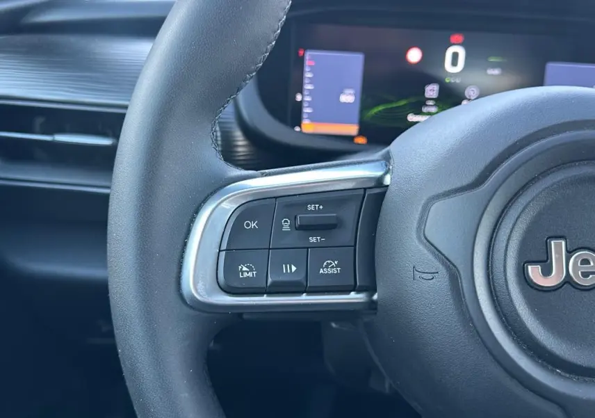 Gros plan sur le volant noir du Jeep Avenger 2025 avec commandes de régulateur et affichage numérique en arrière-plan.