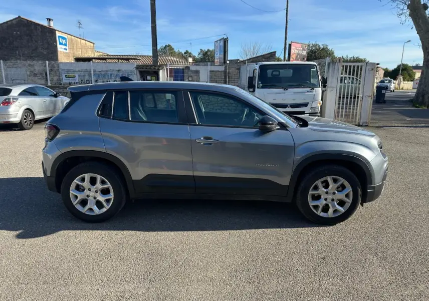 Vue de profil côté gauche d'un Jeep Avenger gris 2025 avec jantes alliage 17 pouces sur un parking extérieur.