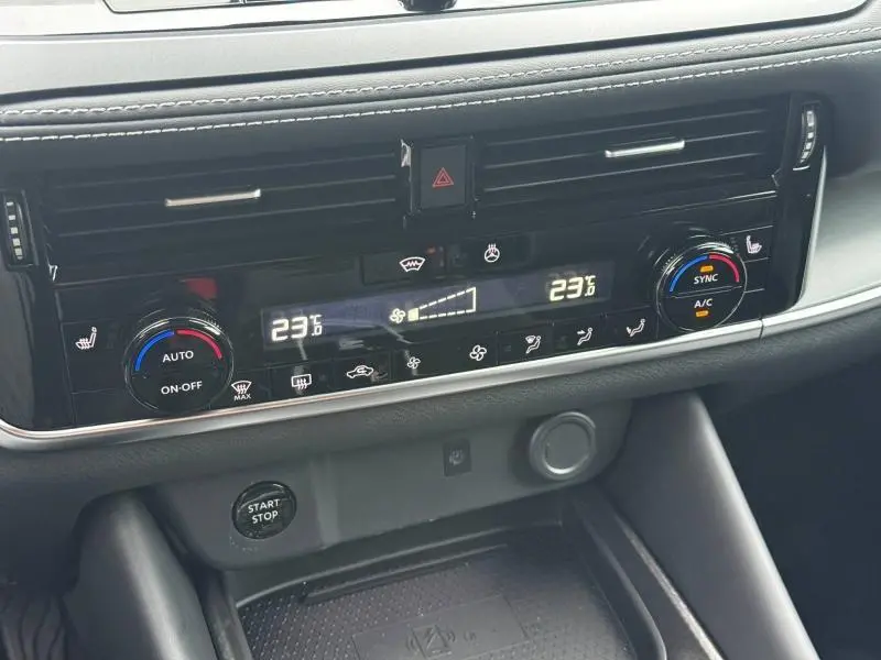Gros plan sur la console centrale du Nissan Qashqai Hybrid e-POWER 2025, montrant les commandes de climatisation et le bouton start/stop.
