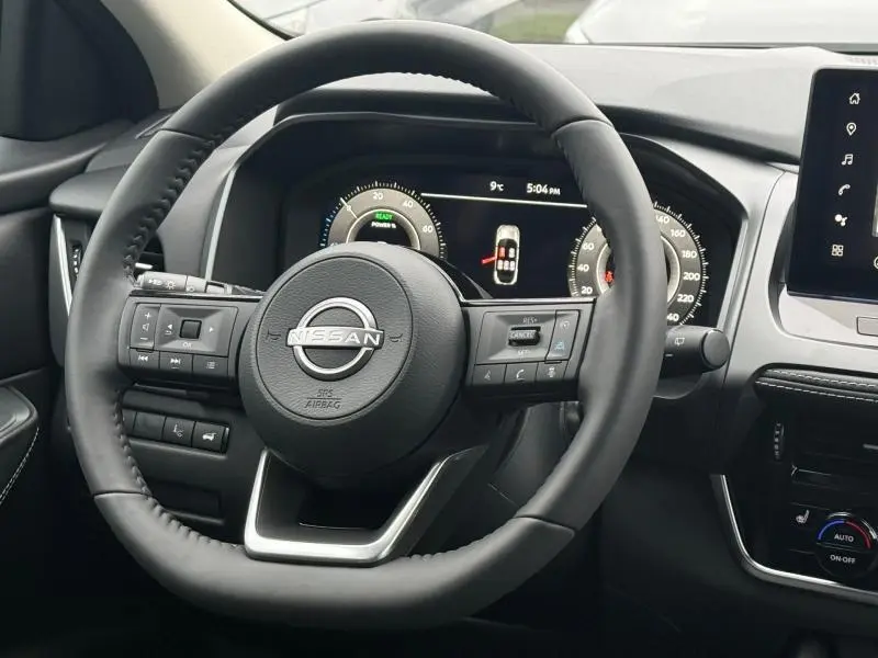 Vue intérieure centrée sur le volant noir du Nissan Qashqai Hybrid e-POWER 2025 avec tableau de bord digital et commandes intégrées.