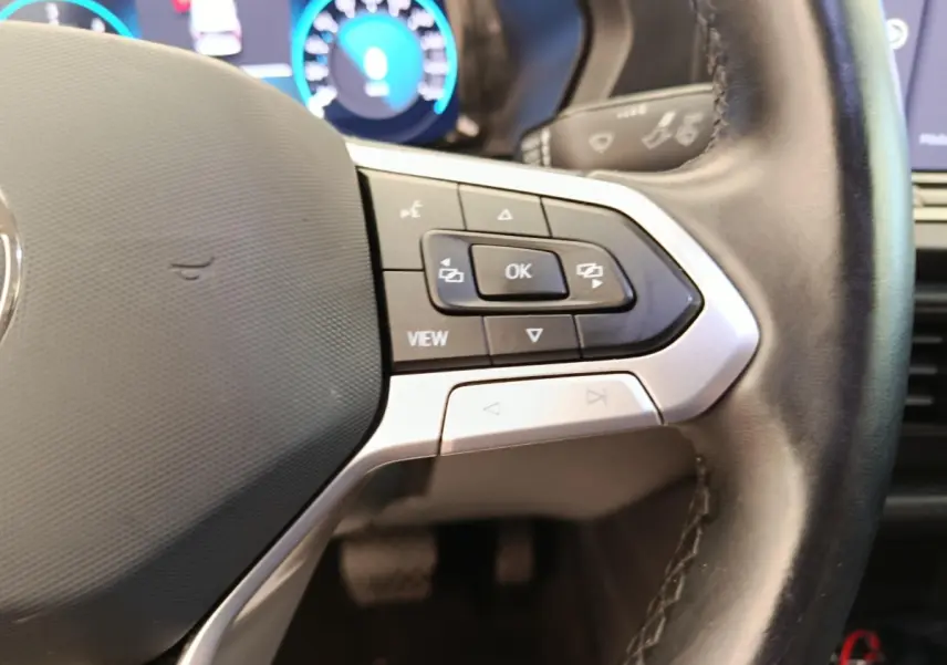 Gros plan sur le volant cuir multifonctions du Volkswagen Caddy 2022 avec commandes intégrées et tableau de bord numérique.