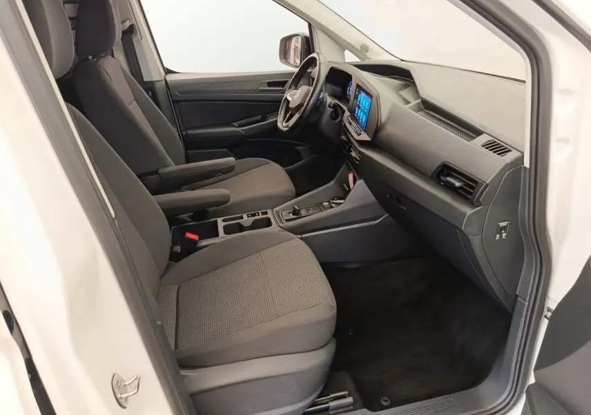 Vue intérieure côté passager du Volkswagen Caddy blanc 2022, mettant en valeur les sièges gris et l'écran tactile central.