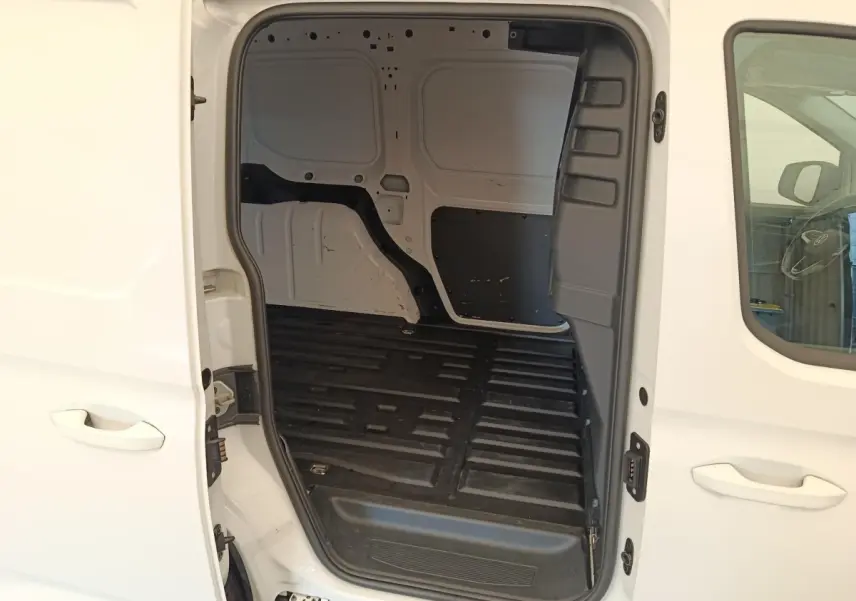 Vue latérale droite du Volkswagen Caddy blanc 2022 avec porte coulissante ouverte montrant l’espace de chargement vide.