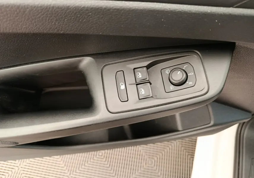 Détail des commandes de réglage des rétroviseurs et des vitres sur la porte côté conducteur d’un Volkswagen Caddy blanc.