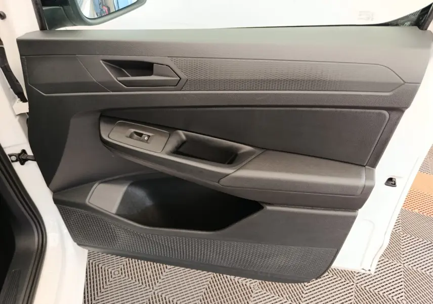 Détail de la porte avant gauche noire du Volkswagen Caddy blanc 2022, avec poignée et commande de vitre électrique.