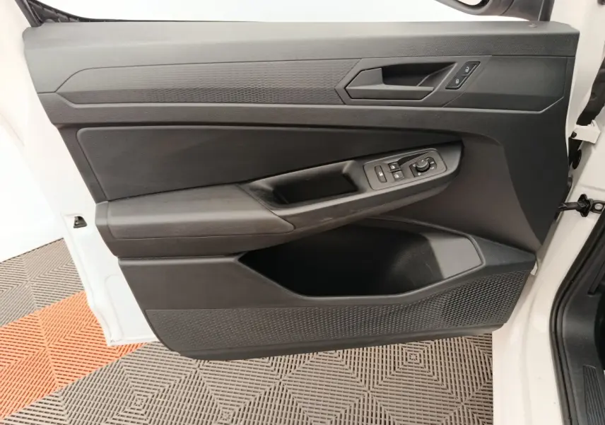 Vue rapprochée de la porte avant gauche blanche du Volkswagen Caddy 2022 avec commandes électriques et poignée noire.