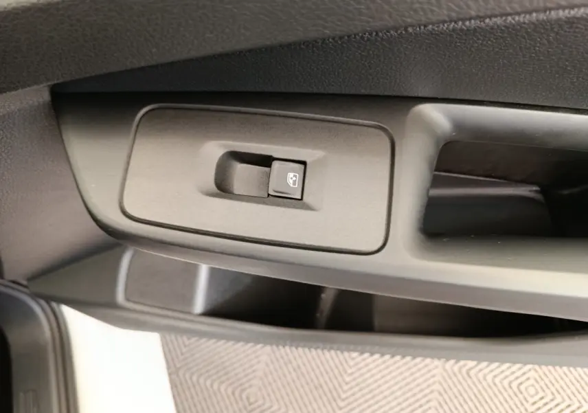 Gros plan sur le bouton de commande de la vitre électrique côté conducteur dans une Volkswagen Caddy blanche.