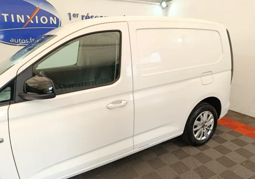 Vue latérale droite d'un utilitaire Volkswagen Caddy blanc avec jantes alliage et rétroviseurs noirs.