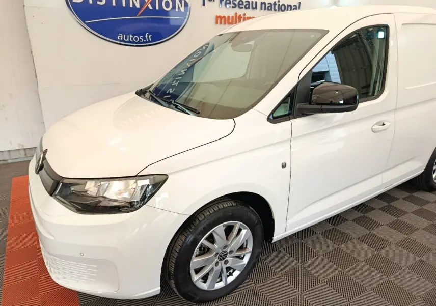 Vue 3/4 avant droit d'un Volkswagen Caddy blanc 2022 avec jantes alliage et rétroviseurs noirs.