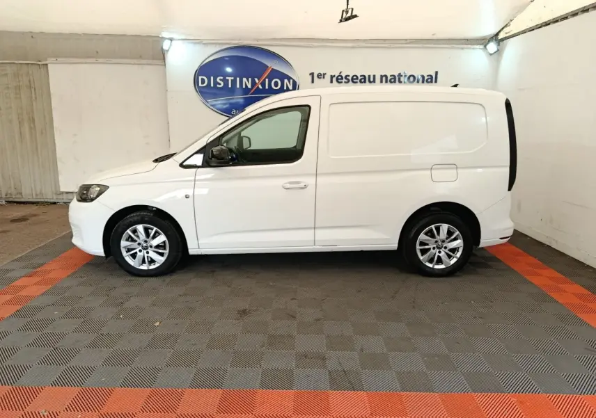 Vue de profil côté gauche d'un Volkswagen Caddy blanc 2022 utilitaire, avec jantes alliage et porte latérale coulissante.
