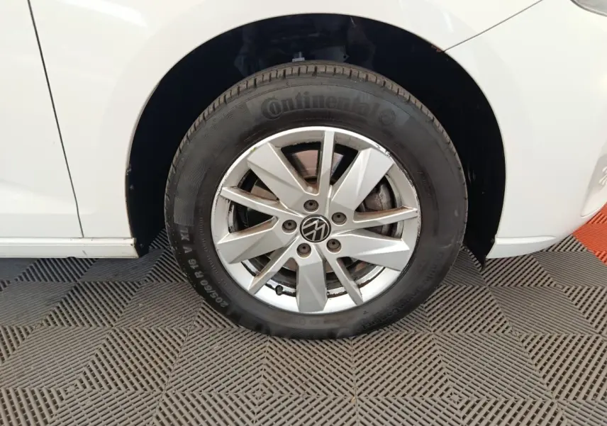 Gros plan sur la roue avant gauche d'un Volkswagen Caddy blanc, mettant en valeur la jante alliage et le pneu Continental.