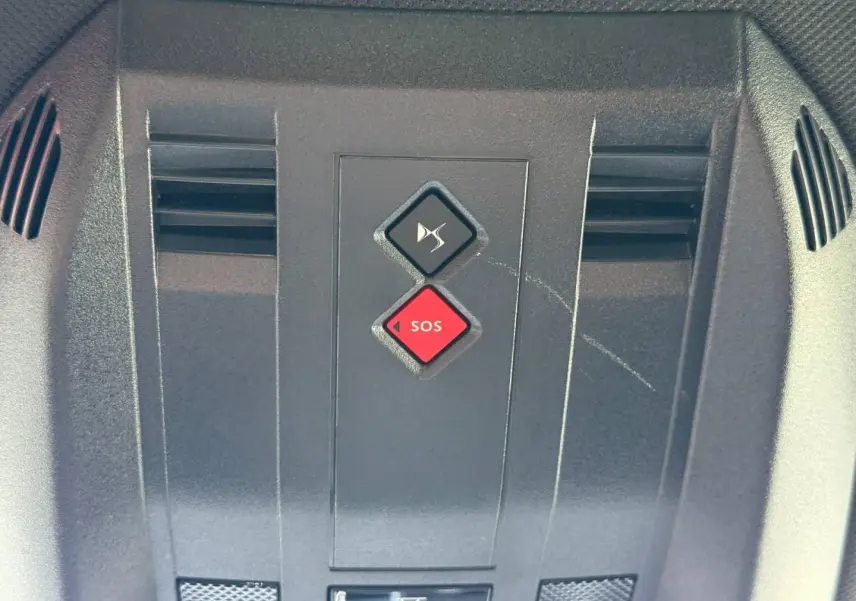 Gros plan sur la console de toit du DS7 E-TENSE 2024, boutons SOS rouge et muet noir visibles.