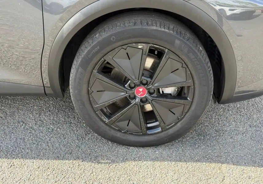 Gros plan sur la roue avant droite du DS7 E-TENSE 2024 en Gris Titane avec jante noire au design géométrique.