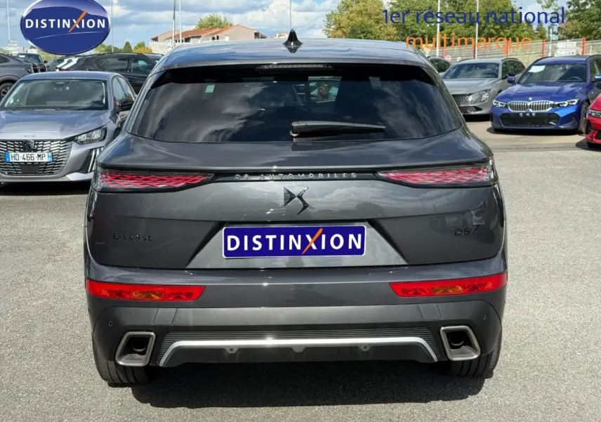 Vue arrière d’un DS7 E-TENSE gris titane 2024 avec feux LED et double sortie d’échappement visible en extérieur.