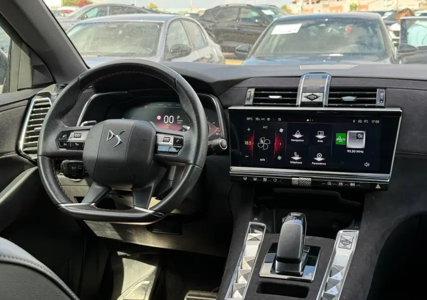 Vue intérieure centrée sur le volant et l’écran tactile du tableau de bord du DS7 E-TENSE gris Titane.