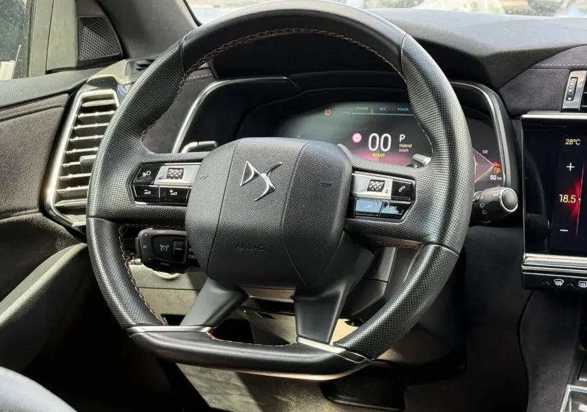 Vue rapprochée du volant cuir noir du DS7 E-TENSE 2024 avec tableau de bord numérique et commandes intégrées.