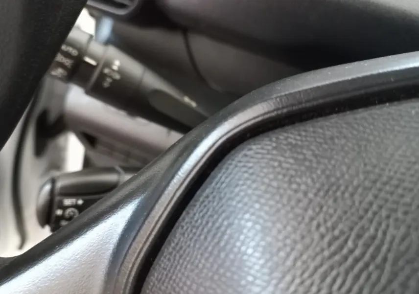 Gros plan sur le volant noir et les commandes derrière sur un Peugeot Partner blanc, vue intérieure côté conducteur.