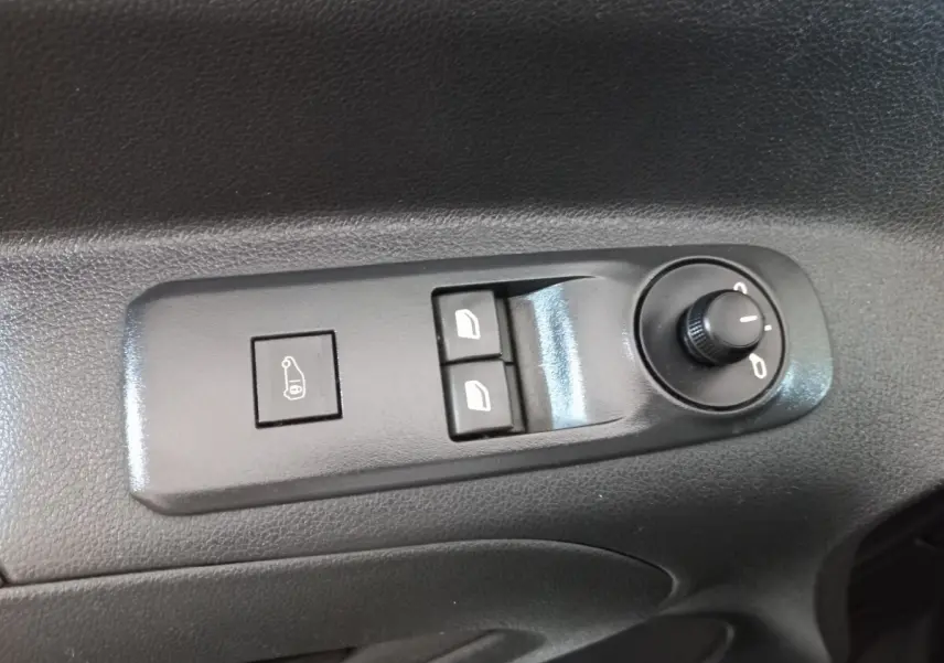 Gros plan sur les commandes de réglage des rétroviseurs et des vitres électriques sur la porte intérieure d'un Peugeot Partner blanc.